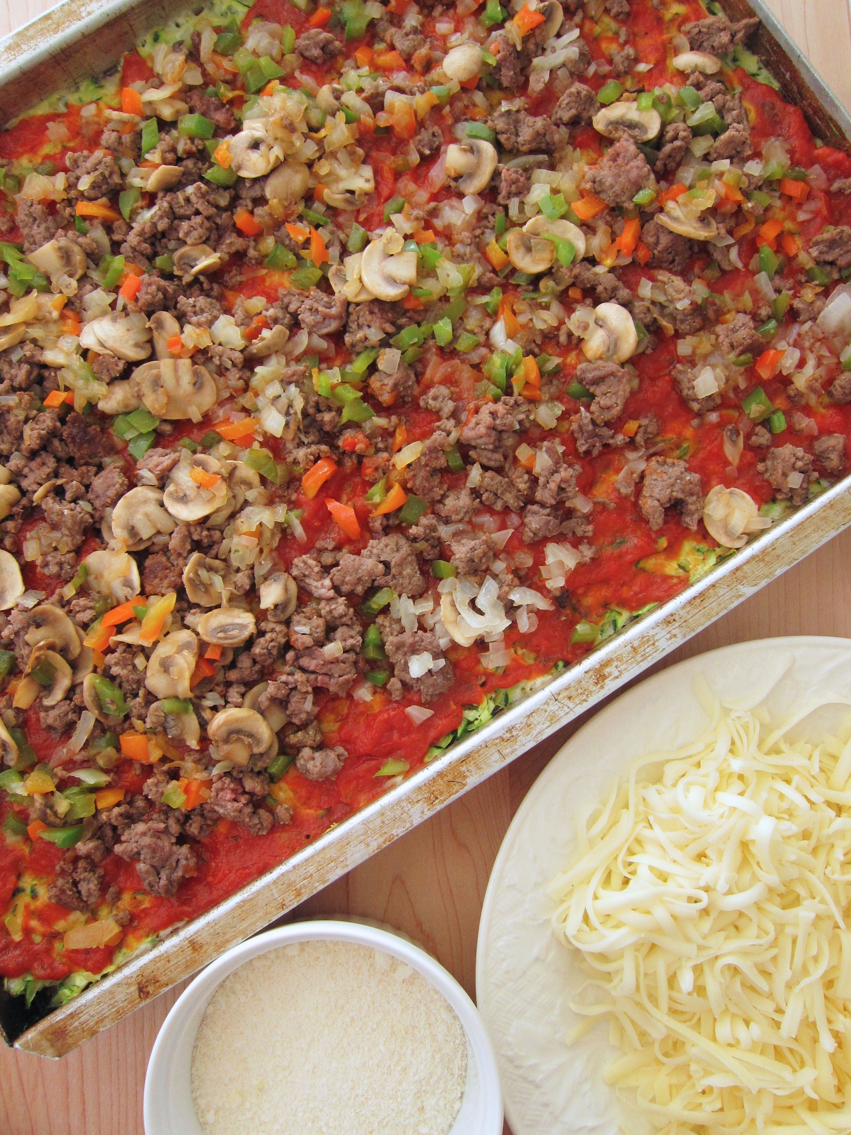 pizza topping on zucchini crust next to cheeses