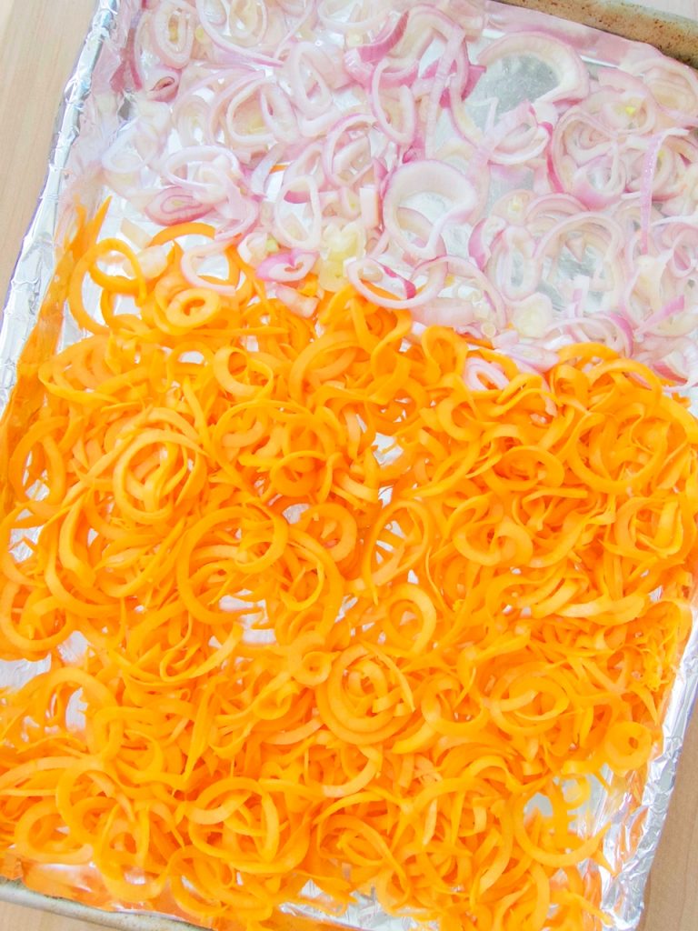 sweet potato noodles and onions on baking sheet