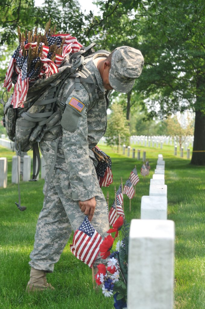 soldier putting flags on graves